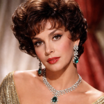 Close-up of a woman with short curly hair wearing emerald and diamond earrings and necklace